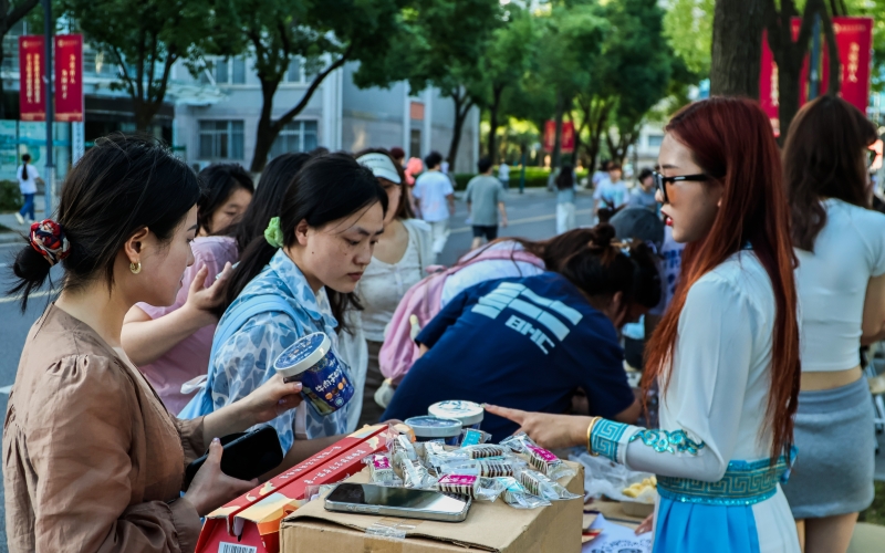 一名学生身着民族服饰向同学推销内蒙古特产。杨培摄